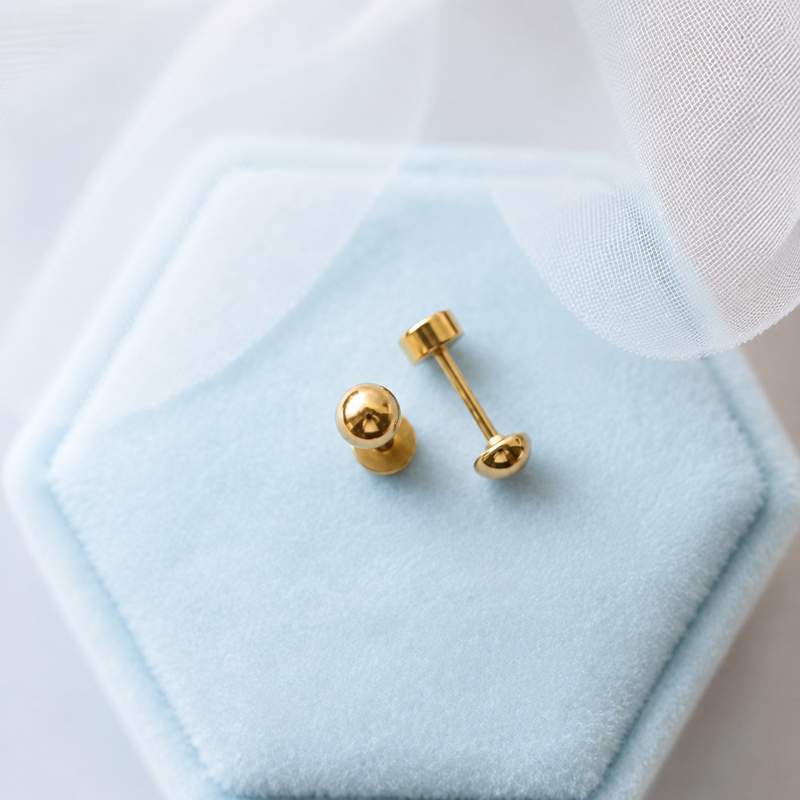 Gold ball stud earrings showing their posts and flat screw-backs